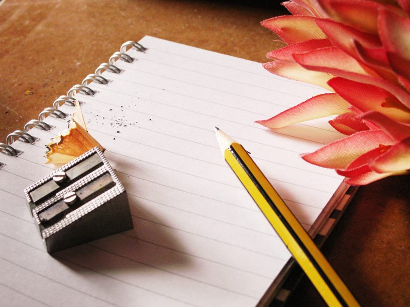 notebook with pencil, pencil sharpener and flower