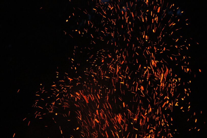 Orange fireworks sparks against a black sky